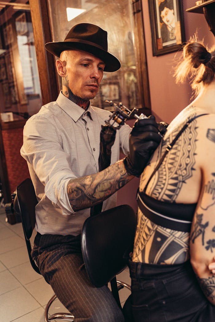 gallery-2 Focused tattoo artist creating detailed blackwork art on client's back in studio